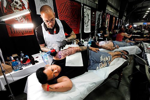 PHIL HOSSACK / WINNIPEG FREE PRESS - Artists and their canvasses at The Third annual Winnipeg Tattoo Convention at the Red River Exhibition Saturday. Canvas Andre Serrano looks away as artist 'Safwon'  who works out of Montreal works on a complex sleeve tattoo.  STANDUP    - August 17, 2019.