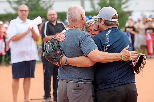 09082023
Bev Neufeld (C), Host Committee Co-Chair, Westman Magic Assistant Coach and mother of Ashley Neufeld, hugs her husband Phil and son Jeff after throwing out the ceremonial first pitch at the opening ceremonies of the U15 Girl's Canadian Fast Pitch Championships at the Ashley Neufeld Softball Complex in Brandon on Wednesday. Ashley Neufeld and two Dickinson State University softball teammates, Kyrstin Gemar and Afton Williamson, died tragically in November, 2009 when the vehicle they were in drove into a pond near the university in North Dakota. 
(Tim Smith/The Brandon Sun)