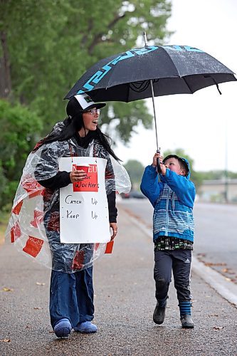 Dennis Grasby, 4, holds an umbrella for Laramie Lockie as she pickets with fellow Manitoba Liquor and Lotteries employees along Aberdeen Avenue across from the Brandon South Liquor Mart on a rainy Thursday as part of a province-wide strike. Grasby’s mom, Brianna Robertson, is also part of the MLL employees currently on strike. For more on the strike, turn to Page A3. (Tim Smith/The Brandon Sun)