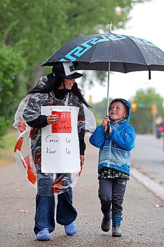 10082023
Four-year-old Dennis Grasby holds an umbrella for Laramie Lockie as she pickets with fellow Manitoba Liquor &amp; Lottery employees along Aberdeen Avenue across from the Brandon South Liquor Mart on a rainy Thursday as part of a province-wide strike. Grasby&#x2019;s mom, Brianna Robertson, is also part of the Manitoba Liquor &amp; Lottery employees currently on strike.
(Tim Smith/The Brandon Sun)