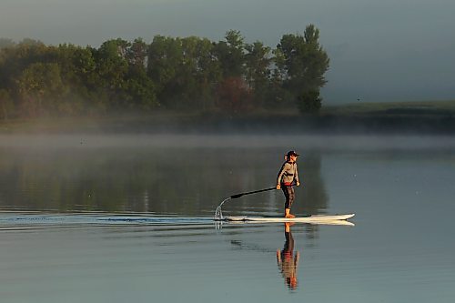 Tracy Ramage paddleboards along the smooth-as-glass surface of Lake Clementi south of Brandon as fog rolls over the lake shortly after sunrise on Monday morning. (Tim Smith/The Brandon Sun)