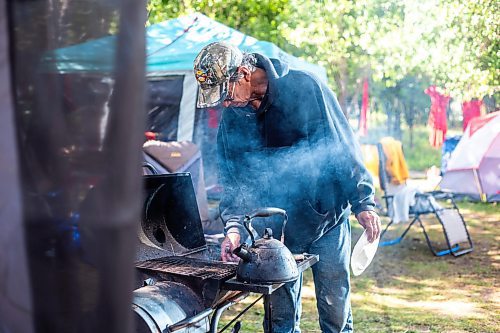 MIKAELA MACKENZIE / WINNIPEG FREE PRESS

Camp elder Marcel Branch boils water on the grill for coffee at Camp Marcedes (beside the Canadian Museum for Human Rights) on Monday, Aug. 14, 2023. For Cierra Bettens story.
Winnipeg Free Press 2023