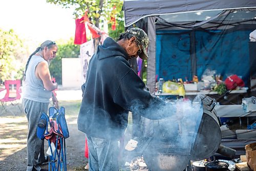 MIKAELA MACKENZIE / WINNIPEG FREE PRESS

Camp elder Marcel Branch boils water on the grill for coffee at Camp Marcedes (beside the Canadian Museum for Human Rights) on Monday, Aug. 14, 2023. For Cierra Bettens story.
Winnipeg Free Press 2023