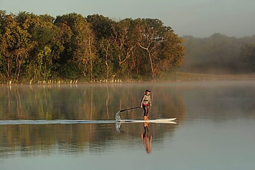 14082023
Tracy Ramage paddleboards along the smooth-as-glass surface of Lake Clementi south of Brandon as fog rolls over the lake shortly after sunrise on Monday morning.
(Tim Smith/The Brandon Sun)