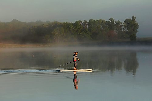 14082023
Tracy Ramage paddleboards along the smooth-as-glass surface of Lake Clementi south of Brandon as fog rolls over the lake shortly after sunrise on Monday morning.
(Tim Smith/The Brandon Sun)