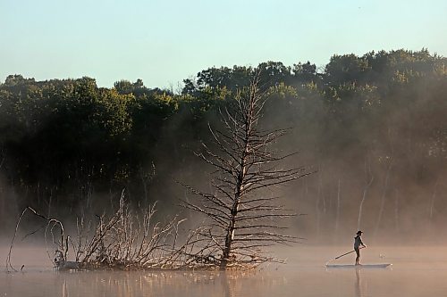 14082023
Tracy Ramage paddleboards along the smooth-as-glass surface of Lake Clementi south of Brandon as fog rolls over the lake shortly after sunrise on Monday morning.
(Tim Smith/The Brandon Sun)