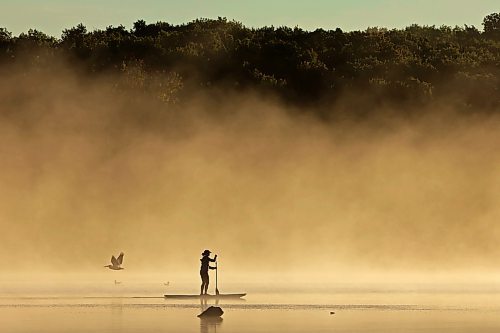 14082023
Tracy Ramage paddleboards along the smooth-as-glass surface of Lake Clementi south of Brandon as fog rolls over the lake shortly after sunrise on Monday morning.
(Tim Smith/The Brandon Sun)