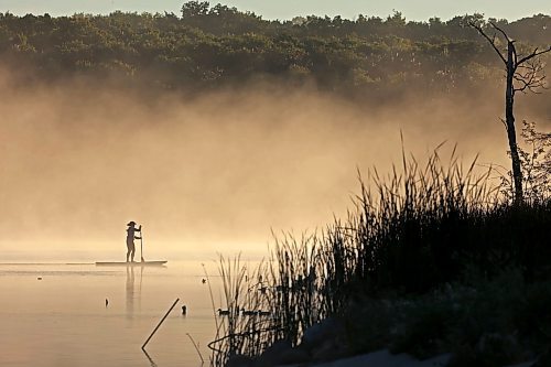 14082023
Tracy Ramage paddleboards along the smooth-as-glass surface of Lake Clementi south of Brandon as fog rolls over the lake shortly after sunrise on Monday morning.
(Tim Smith/The Brandon Sun)