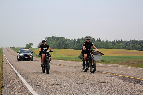 Brandon Police Service officers Cst. Selena Samagalski and Cst. Meghan Puteran cycle along Highway 468 east of Brandon with Cst . Denis Dufault in the police cruiser for safety. The BPS officers accompanied Shilo soldier Rob Nederlof from Brandon to Shilo on his 1,000 kms trek to raise funds and awareness for the Wounded Warrior PTSD Service Dogs program on Tuesday. (Michele McDougall/The Brandon Sun)