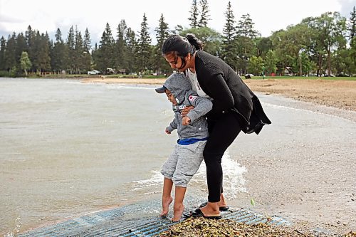 16082023
Charlot Asejo dips her son Charles&#x2019; feet in the cool water of Clear Lake at the beach in Wasagaming during a family trip to Riding Mountain National Park on a very windy Wednesday afternoon. Four-year-old Charles has autism and loves water. 
(Tim Smith/The Brandon Sun)