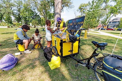 MIKE DEAL / WINNIPEG FREE PRESS
The West Broadway Youth Outreach Book Bike made a stop in Vimy Ridge Park Thursday. The Book Bike incentivizes reading by getting children to read ten books to a WBYO staff member in return for a free ice cream.
(From left) Takuto Yokoyama an exchange student working with WBYO listens to Rufta, 11, read a book while Errata, 8, reads to Vex Young a WBYO staff member in Vimy Ridge Park Thursday. 
230817 - Thursday, August 17, 2023.