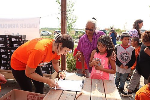 18082023
Tr&#xe9;chelle Bunn, founder of the Reconciliation Run, hands out pairs of Under Armour shoes to children at the Birdtail Sioux First Nation Healing Garden on Friday. Bunn organized the donation of 213 pairs of shoes from Under Armour for children at Birdtail and helped hand out the shoes with other volunteers. Community members could also sign up for the 2023 Reconciliation Run at the event.   (Tim Smith/The Brandon Sun)