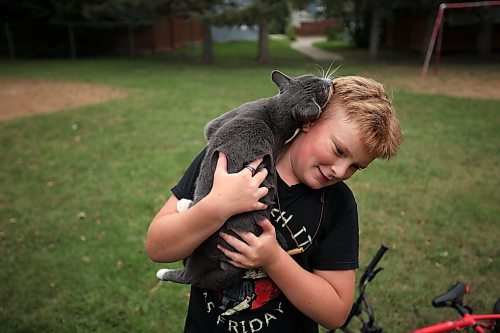 21082023
Levi Wiebe visits with a neighbourhood cat while hanging riding at the bike tracks on 3rd Street in Brandon&#x2019;s south end with friends on Monday. 
(Tim Smith/The Brandon Sun)