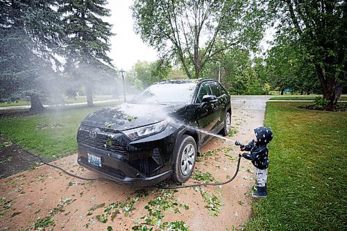 MIKE DEAL / WINNIPEG FREE PRESS
Leo Spacek, 2, washes leaves off the family car the morning after a storm ripped through the East Kildonan area knocking down tree limbs and damaging property with hail.
230825 - Friday, August 25, 2023.