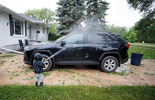 MIKE DEAL / WINNIPEG FREE PRESS
Leo Spacek, 2, washes leaves off the family car the morning after a storm ripped through the East Kildonan area knocking down tree limbs and damaging property with hail.
230825 - Friday, August 25, 2023.