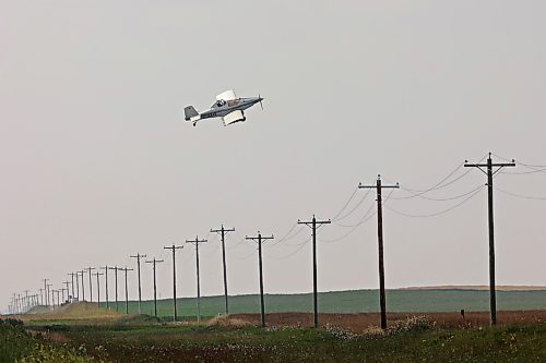 An aerial sprayer flies low over power lines while spraying a crop near Margaret on Monday afternoon. (Tim Smith/The Brandon Sun)