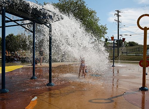 Two young girls drenched and almost invisible from the big bucket splash at Rideau Splash Park Wednesday afternoon in Brandon. (Michele McDougall/The Brandon Sun)
