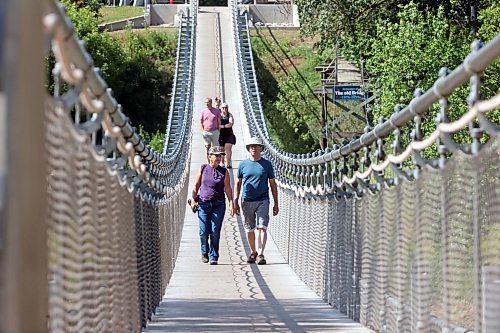 Yves Gagnon and Diane Charlebois from Montreal walk across the Souris Swinging Bridge on a warm Wednesday afternoon. (Matt Goerzen/The Brandon Sun)