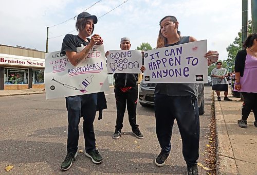 Three participants of a march in honour of International Overdose Awareness Day hold up signs on Thursday afternoon at Princess Park in Brandon, where the day's events were held. (Matt Goerzen/The Brandon Sun)
