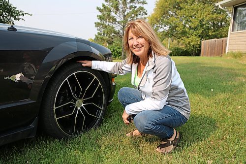 Patsy Desjardin crouches beside her front 10 inch tire with its Petrol rim on her 2008 Mustang in Brandon on Thursday. (Michele McDougall/The Brandon Sun) 
