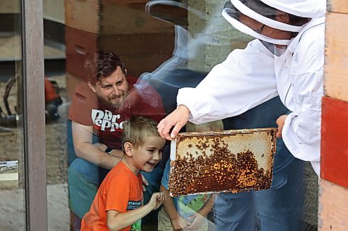 Deanna Smid, a Brandon University professor and co-ordinator of the Bee U program, shows a frame of honeycomb to onlookers as members of the program collect honeycombs on Tuesday evening. See more photos on Page A3. (Tim Smith/The Brandon Sun)