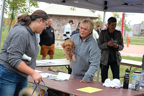 Volunteer Brenda Cavanagh, with her friend Gunni tucked under her arm, chats with a fellow dog lover Sunday morning at Kin Park during Brandon Humane Society’s 20th Wag-A-Tail Walk-A-Thon event.  (Kyle Darbyson/The Brandon Sun)