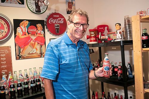 BROOK JONES / WINNIPEG FREE PRESS
Winnipegger Morris Glimcher, who was the executive director of the Manitoba High Schools Athletic Association from 1975 to 2016, shows off his Coca-Cola collection of bottles and memorabilia in his rec room at his home in Winnipeg, Man., Wednesday, Sept. 13, 2023. Glimcher is pictured holding an American Idol Coca-Cola bottle.