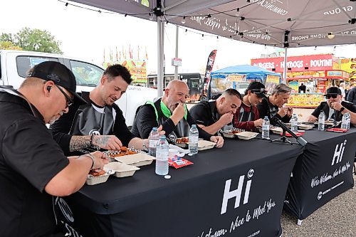 The participants of the Westman Communication Group’s first-ever Celebrity Hot Wings Challenge get down to business at the Keystone Centre parking lot on Saturday afternoon. They are, from left to right, Ryan Hackett (Sobeys franchise owner), Colby Robak (professional hockey player), Bud Keys (WCG president), Rene Lariviere (personal trainer), Austin Dobrescu (professional golfer), Frank McGwire (radio personality) and Jeff Kulman (audience participant). (Kyle Darbyson/The Brandon Sun)