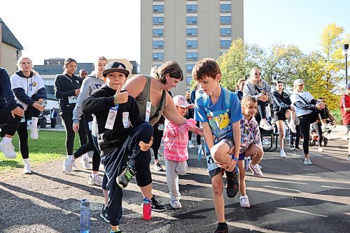 Participants of the 2023 Terry Fox Run take part in a group warm-up on Sunday morning before departing from Brandon University. (Kyle Darbyson/The Brandon Sun)