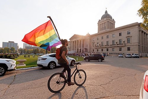 MIKE DEAL / WINNIPEG FREE PRESS
Trans Rights supporter, Christian Bethge, rides his bike while flying a rainbow flag at the Manitoba Legislative building Wednesday morning.
230920 - Wednesday, September 20, 2023.