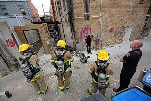 A member of the Brandon Police Service inspects burned garbage that has been spread out at the south end brick wall of the Laplont block on Wednesday afternoon in downtown Brandon. Emergency crews, including Brandon police and fire, attended the scene of a garbage fire that appeared to have spread to a back gate of the property. (Matt Goerzen/The Brandon Sun)
