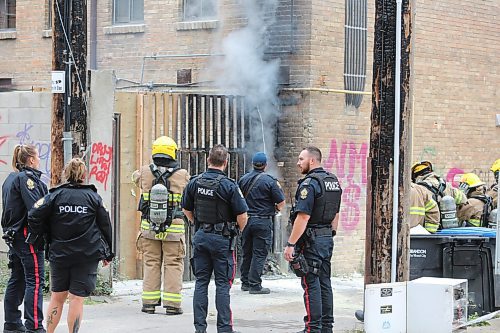 A Brandon firefighter sprays water on a burning wooden frame on the south end brick wall of the Laplont block on Wednesday afternoon in downtown Brandon. Emergency crews, including Brandon police and fire, attended the scene of a garbage fire that appeared to have spread to a back gate of the property. (Matt Goerzen/The Brandon Sun)