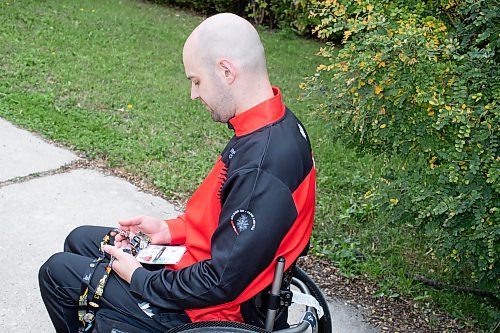 BROOK JONES / WINNIPEG FREE PRESS
Twenty-nine-year-old Lealand Muller, who represented Canada at the 2023 Invictus Games in D&#xfc;sseldorf, Germany from Sept. 9 to 16, looks at various pins he collected at the game. Muller is pictured in his front yard at his home in Winnipeg, Man., Thursday, Sept. 21, 2023 and competed in hand cycle, discuss and wheelchair basketball. Canada will play host to the 2025 Invictus Game in Vancouver and Whistler. 