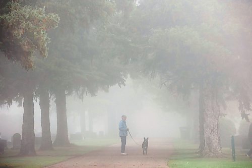 26092023
A woman walks a dog through the fog at the Brandon Municipal Cemetery on a cool Tuesday morning. Thick fog blanketed the wheat city throughout the morning. 
(Tim Smith/The Brandon Sun)