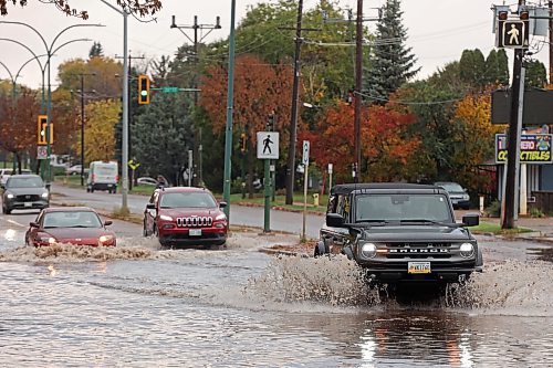Vehicles drive through deep water flooding on Richmond Avenue west of 18th Street after a thunderstorm and downpour on Thursday morning. (Tim Smith/The Brandon Sun)