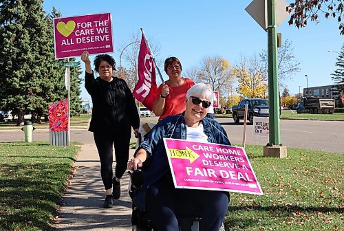 Helen Janzen, a resident of Valleyview Extendicare wheeled down the sidewalk alongside support staff carrying a sign that said Care home workers deserve a fair deal in Brandon on Friday. (Michele McDougall/The Brandon Sun)