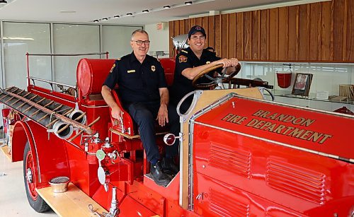 Capt. Marv Janzen and Lt. Kevin Garrioch with Brandon Fire and Emergency Services sit on the 1929 Bickle fire truck, in the museum at Brandon’s No. 1 Fire Hall, 120 19th Street North, on Thursday. (Michele McDougall/The Brandon Sun)