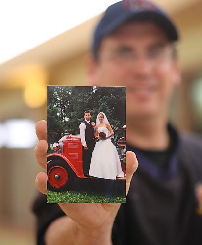 Lt. Kevin Garrioch with Brandon Fire and Emergency Services holds a wedding photo with his wife Fiona, taken July 16, 2005, in front of the 1929 Bickle fire truck. (Matt Goerzen/The Brandon Sun)
