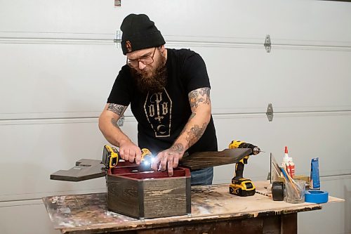 BROOK JONES / WINNIPEG FREE PRESS
Blake Locken, who works as a carpenter by day, runs a home-based business called Old Pine Box Curiousitiies. Locken is pictured working on a coffin shaped cabinet in his garage, which dubs as his workshop, in Winnipeg, Man., Wednesday, Oct. 11 . He also builds upholstered pet beds and charcuterie boards, all with a coffin shape theme. The Winnipeg resident will be a vendor at the Punk Rock Flea Market at the University of Manitoba in Winnipeg, Man., Saturday, Oct. 14, 2023 from 10:30 a.m. to 5 p.m. The event also run Sunday, Oct. 15, 2023.