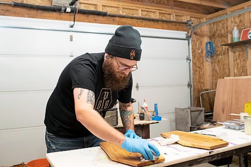 BROOK JONES / WINNIPEG FREE PRESS
Blake Locken, who works as a carpenter by day, runs a home-based business called Old Pine Box Curiousitiies. Locken is pictured sanding a coffin-shaped charcuterie board while working in his garage, which dubs as his workshop, in Winnipeg, Man., Wednesday, Oct. 11 . He also builds upholstered pet beds and cabinets, all with a coffin shape theme. The Winnipeg resident will be a vendor at the Punk Rock Flea Market at the University of Manitoba in Winnipeg, Man., Saturday, Oct. 14, 2023 from 10:30 a.m. to 5 p.m. The event also run Sunday, Oct. 15, 2023.