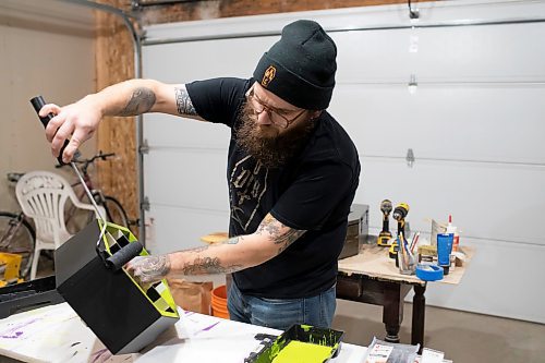 BROOK JONES / WINNIPEG FREE PRESS
Blake Locken, who works as a carpenter by day, runs a home-based business called Old Pine Box Curiousitiies. Locken is pictured painting a coffin-shaped shelf while working in his garage, which dubs as his workshop, in Winnipeg, Man., Wednesday, Oct. 11 . He also builds upholstered pet beds and charcuterie boards, all with a coffin shape theme. The Winnipeg resident will be a vendor at the Punk Rock Flea Market at the University of Manitoba in Winnipeg, Man., Saturday, Oct. 14, 2023 from 10:30 a.m. to 5 p.m. The event also run Sunday, Oct. 15, 2023.