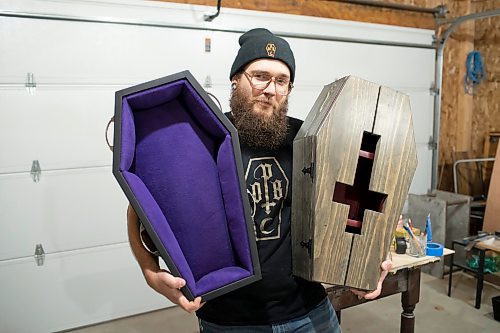 BROOK JONES / WINNIPEG FREE PRESS
Blake Locken, who works as a carpenter by day, runs a home-based business called Old Pine Box Curiousitiies. Locken is pictured holding a coffin-shaped pet bed as well as a coffin shaped cabinet in his garage, which dubs as his workshop, in Winnipeg, Man., Wednesday, Oct. 11 . He also builds charcuterie boards, coffee tables, book shelves and wine racks.  The Winnipeg resident will be a vendor at the Punk Rock Flea Market at the University of Manitoba in Winnipeg, Man., Saturday, Oct. 14, 2023 from 10:30 a.m. to 5 p.m. The event also run Sunday, Oct. 15, 2023.