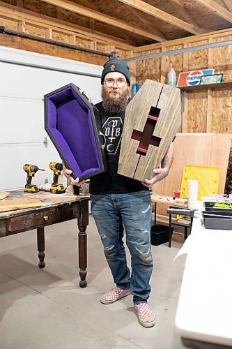 BROOK JONES / WINNIPEG FREE PRESS
Blake Locken, who works as a carpenter by day, runs a home-based business called Old Pine Box Curiousitiies. Locken is pictured holding a coffin-shaped pet bed as well as a coffin shaped cabinet in his garage, which dubs as his workshop, in Winnipeg, Man., Wednesday, Oct. 11. He also builds charcuterie boards, coffee tables, book shelves and wine racks. The Winnipeg resident will be a vendor at the Punk Rock Flea Market at the University of Manitoba in Winnipeg, Man., Saturday, Oct. 14, 2023 from 10:30 a.m. to 5 p.m. The event also run Sunday, Oct. 15, 2023.