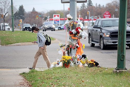 A pedestrian walks by a Victoria Avenue memorial to 15-year-old Antoine Sutherland, who was killed in a bike-vehicle collision at the same Victoria Avenue crosswalk. The memorial is made of flowers, photos, stuffed animals and other items as a remembrance of the Vincent Massey High School student. (Matt Goerzen/The Brandon Sun)