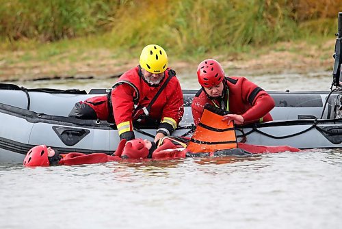 A student from the Manitoba Emergency Services College in Brandon straps on a harness from a floatation stretcher to another student during surface water rescue education in the Assiniboine River as part of their course work at Dinsdale Park on Wednesday afternoon. (Matt Goerzen/The Brandon Sun)