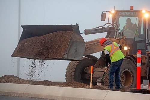 A construction crew works along the shoulder of the new section of the Daly Overpass on a foggy Thursday morning. (Matt Goerzen/The Brandon Sun)