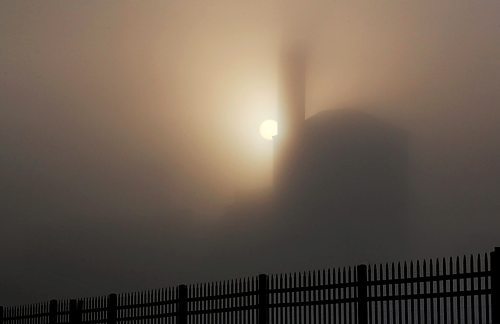The shadowy silhouette of the McKenzie Seeds building towers above the city on a foggy Thursday morning, as seen from Assiniboine Avenue. (Matt Goerzen/The Brandon Sun)