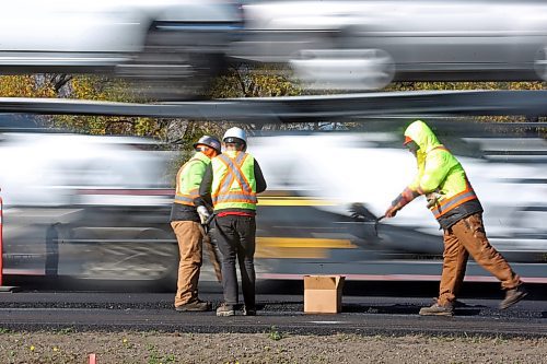 A construction crew evens out the ashphalt on a resurfacing job of the eastbound land of the Trans-Canada Highway in Brandon while a semi-truck passes behind them on Friday afternoon. The construction is part of a $5.75 million upgrade to a 2.2-kilometre stretch of the Trans-Canada Highway announced by the former Progressive Conservative governent of Manitoba in 2022. As part of the project, the province is resurfacing the eastbound and westbound lanes of the highway between the two junctions of Highway 10, and an additional 300 metres of road in both directions. (Matt Goerzen/The Brandon Sun)