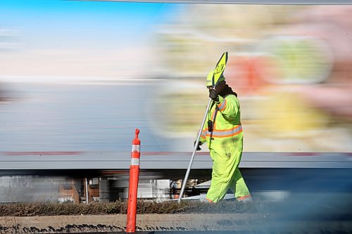 A construction worker holding a traffic sign walks down the middle of the Trans-Canada Highway in Brandon while a semi-truck passes behind him on Friday afternoon. The construction is part of a $5.75 million upgrade to a 2.2-kilometre stretch of the Trans-Canada Highway announced by the former Progressive Conservative governent of Manitoba in 2022. As part of the project, the province is resurfacing the eastbound and westbound lanes of the highway between the two junctions of Highway 10, and an additional 300 metres of road in both directions. (Matt Goerzen/The Brandon Sun)