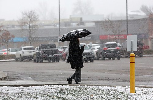 A woman with a snow-covered umbrella walks along the sidewalk near the Shoppers Mall during some Wednesday afternoon snowfall in Brandon. (Matt Goerzen/The Brandon Sun)